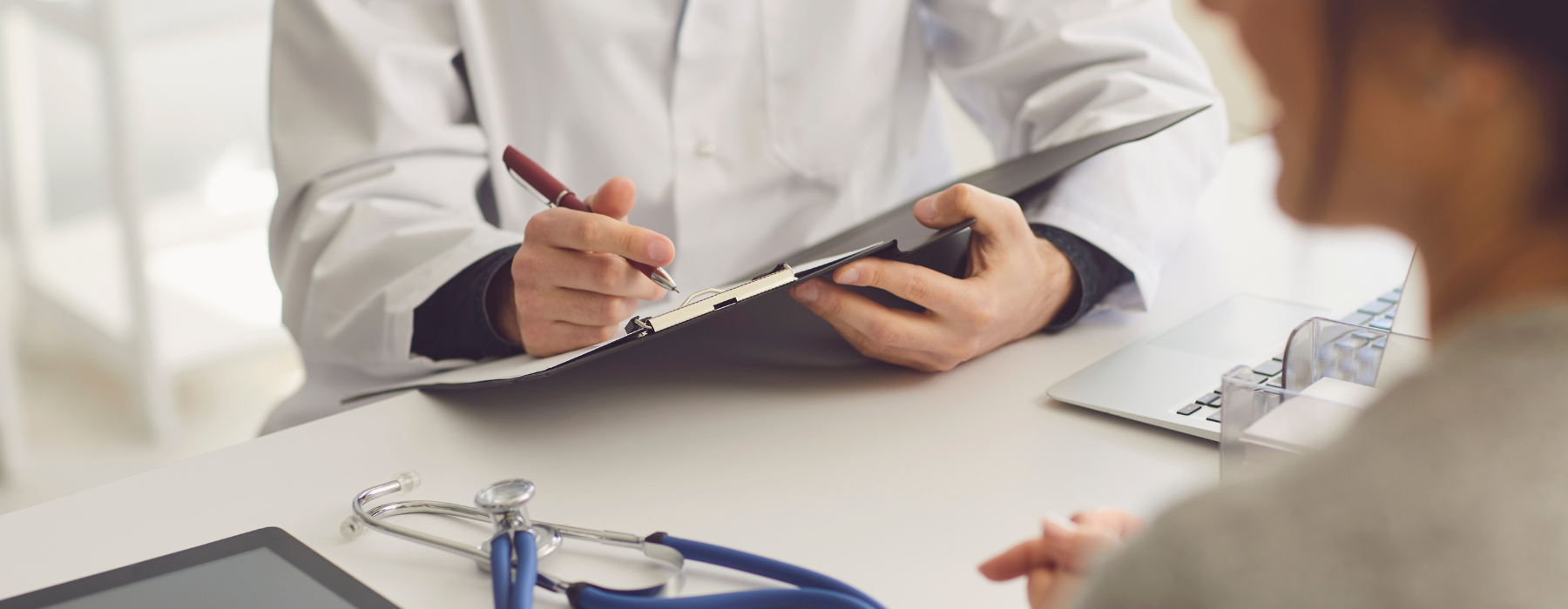 Médico explicando informações em uma prancheta durante consulta com paciente — jornada do paciente em foco.