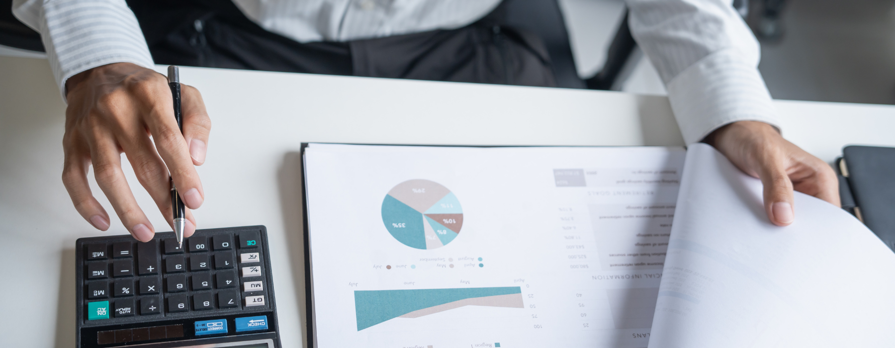 Pessoa analisando relatórios e gráficos financeiros com calculadora, representando o Revenue Cycle Management em instituições de saúde.