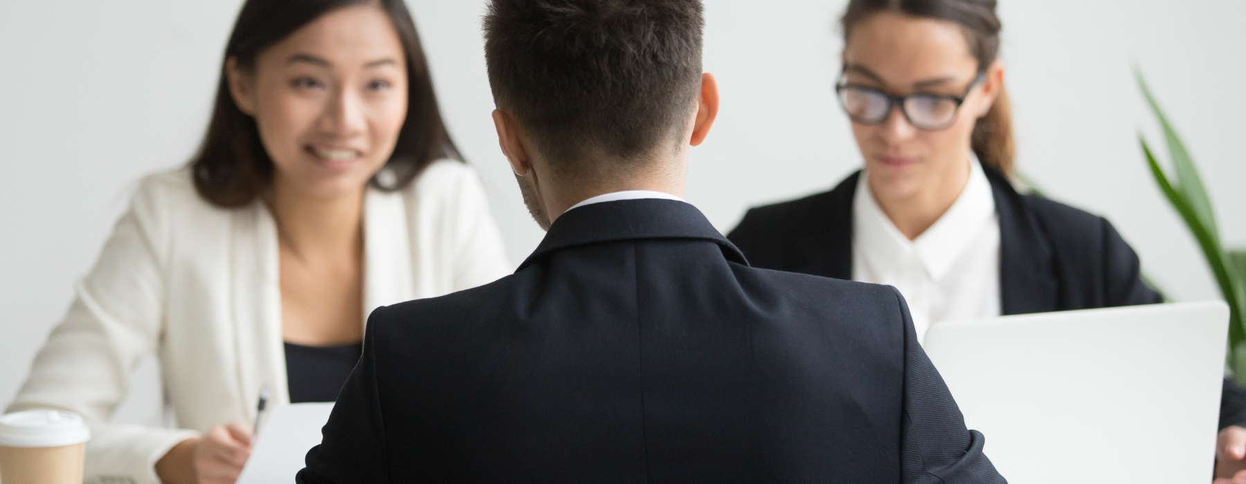 gestão de processos: Homem sendo entrevistado por duas recrutadoras em um escritório durante processo seletivo.