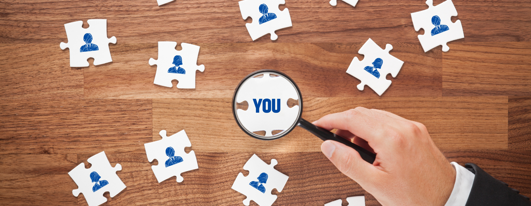 Lupa destacando uma peça de quebra-cabeça com a palavra “YOU” entre peças com ícones de pessoas, representando o foco das Humanized brands no indivíduo.
